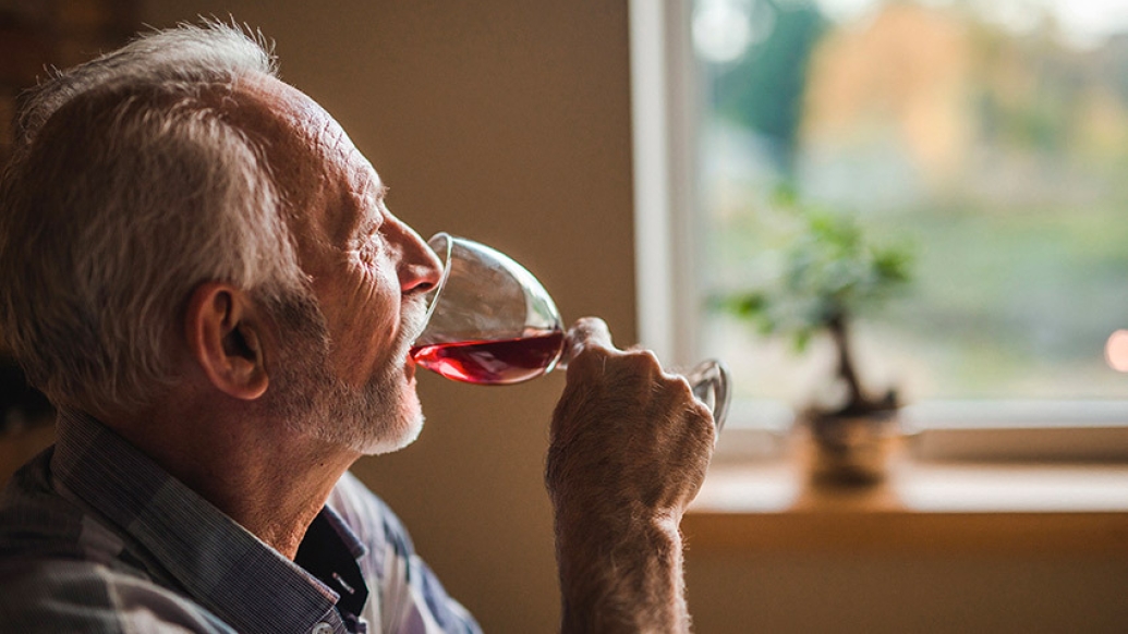 older man drinking red wine from glass