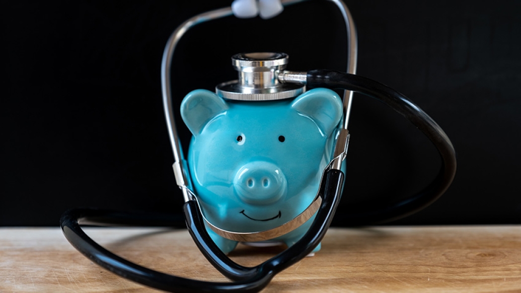 Teal Piggy Bank with Stethoscope on Desk