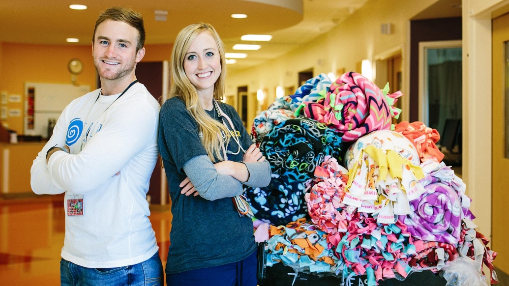 Tara and Nicholas Kristock and a pile of donated fleece blankets